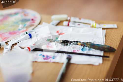 Image of palette knife, brushes and paint on paper tissue