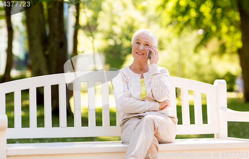 Image of happy senior woman calling on smartphone in summer