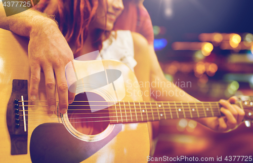 Image of close up of couple with guitar over night lights