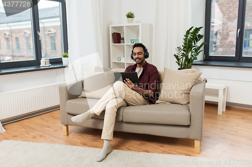 Image of man in phones with tablet pc listening to music