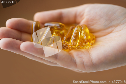 Image of hand holding cod liver oil capsules