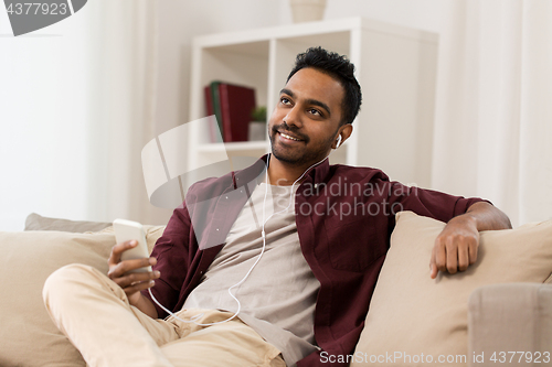 Image of man in earphones listening to music on smartphone