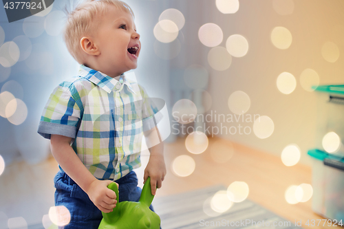 Image of happy baby boy playing with ride-on toy at home