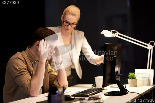 Image of business team with computer working late at office