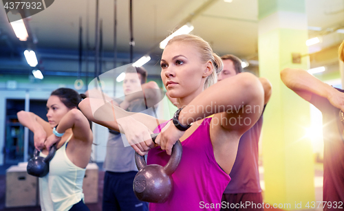 Image of group of people with kettlebells exercising in gym