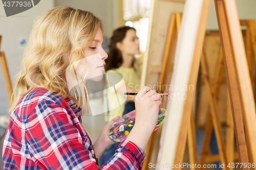 Image of girl with easel painting at art school studio