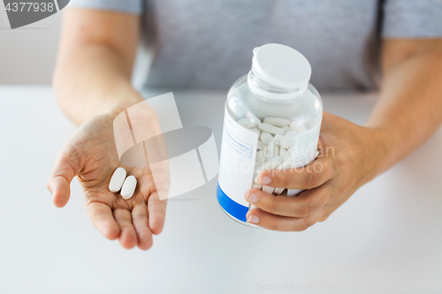 Image of close up of hands holding medicine pills and jar