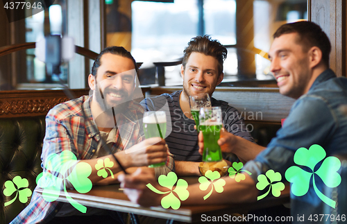 Image of friends taking selfie with green beer at pub
