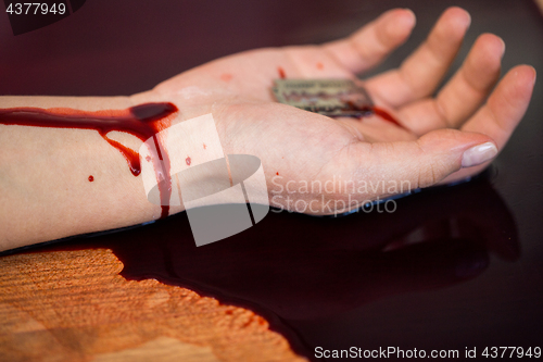 Image of dead woman hand in blood on floor at crime scene
