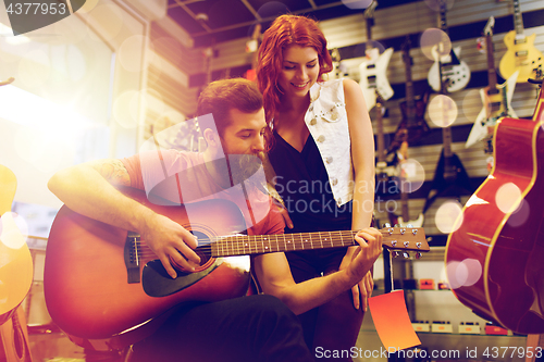 Image of couple of musicians playing guitar at music store