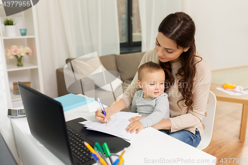 Image of happy mother with baby and papers working at home