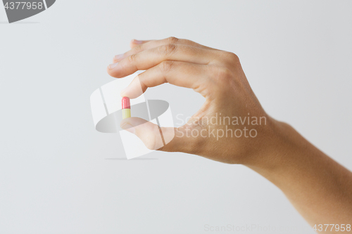 Image of close up of hand holding capsule of medicine