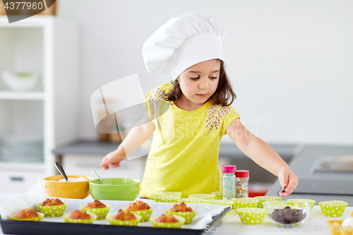 Image of little girl in chefs toque baking muffins at home