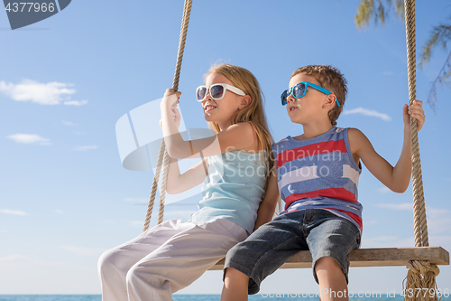 Image of Two happy little children playing on the beach at the day time.