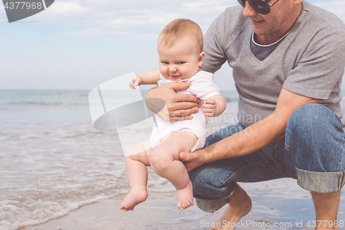 Image of Father and son playing on the beach at the day time.