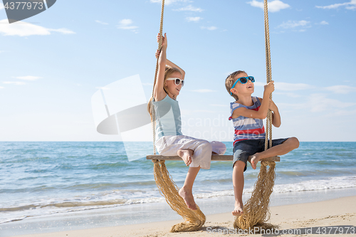 Image of Two happy little children playing on the beach at the day time.