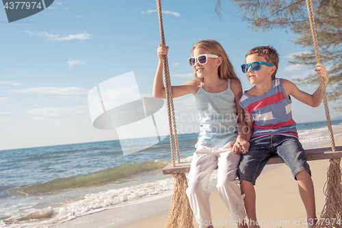 Image of Two happy little children playing on the beach at the day time.