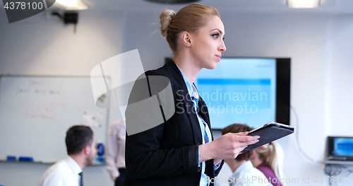 Image of Businesswoman using tablet with coworkers in backgorund having m