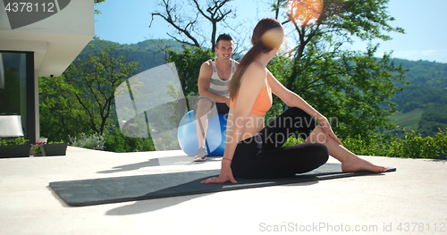 Image of Couple Doing Stretching Exercises Together in front of luxury vi