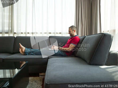 Image of Man using laptop in living room