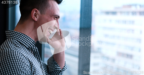 Image of Business Man Talking On Cell Phone, Looking Out Office Window