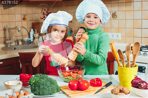 Image of happy family funny kids are preparing the a fresh vegetable salad in the kitchen