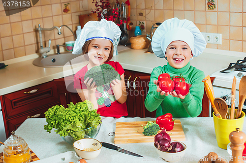 Image of happy family funny kids are preparing the a fresh vegetable salad in the kitchen