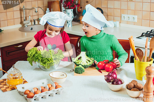 Image of happy family funny kids are preparing the a fresh vegetable salad in the kitchen