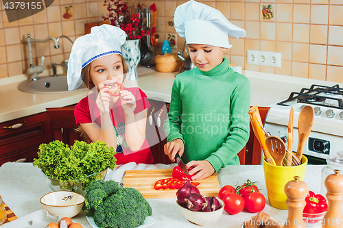 Image of happy family funny kids are preparing the a fresh vegetable salad in the kitchen