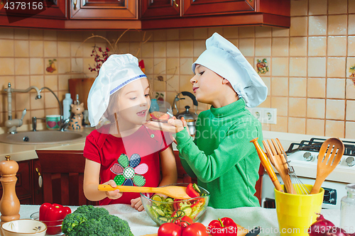 Image of happy family funny kids are preparing the a fresh vegetable salad in the kitchen