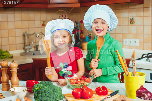 Image of happy family funny kids are preparing the a fresh vegetable salad in the kitchen