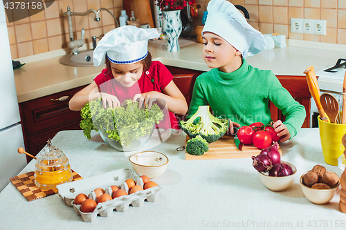 Image of happy family funny kids are preparing the a fresh vegetable salad in the kitchen