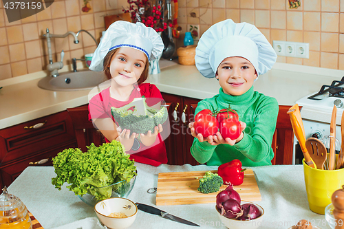 Image of happy family funny kids are preparing the a fresh vegetable salad in the kitchen