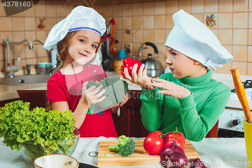 Image of happy family funny kids are preparing the a fresh vegetable salad in the kitchen