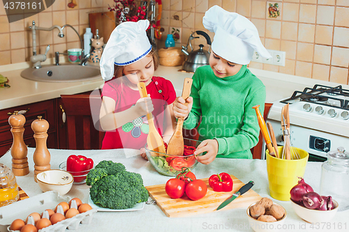 Image of happy family funny kids are preparing the a fresh vegetable salad in the kitchen