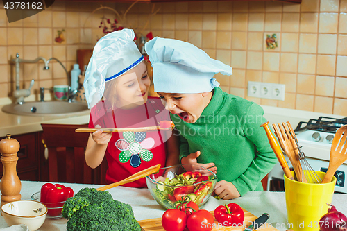 Image of happy family funny kids are preparing the a fresh vegetable salad in the kitchen