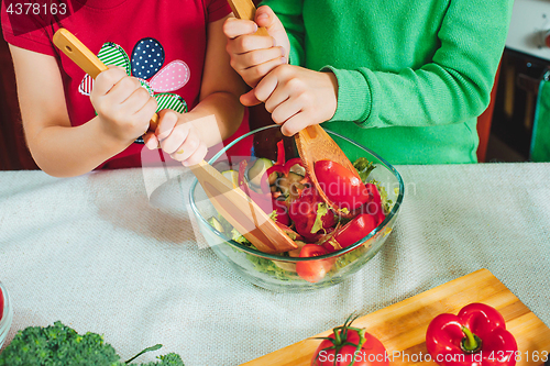 Image of happy family funny kids are preparing the a fresh vegetable salad in the kitchen