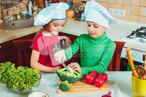 Image of happy family funny kids are preparing the a fresh vegetable salad in the kitchen