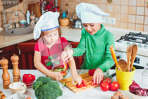 Image of happy family funny kids are preparing the a fresh vegetable salad in the kitchen