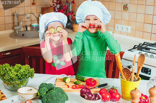 Image of happy family funny kids are preparing the a fresh vegetable salad in the kitchen