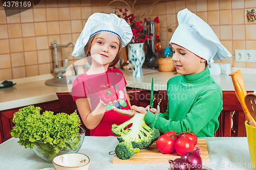 Image of happy family funny kids are preparing the a fresh vegetable salad in the kitchen