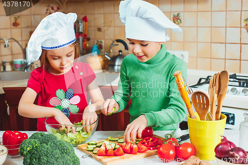 Image of happy family funny kids are preparing the a fresh vegetable salad in the kitchen