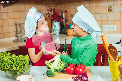 Image of happy family funny kids are preparing the a fresh vegetable salad in the kitchen