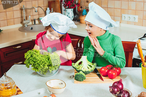 Image of happy family funny kids are preparing the a fresh vegetable salad in the kitchen