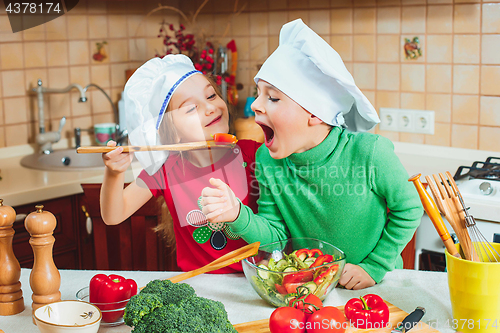 Image of happy family funny kids are preparing the a fresh vegetable salad in the kitchen