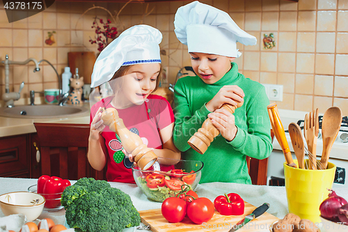 Image of happy family funny kids are preparing the a fresh vegetable salad in the kitchen