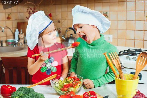 Image of happy family funny kids are preparing the a fresh vegetable salad in the kitchen