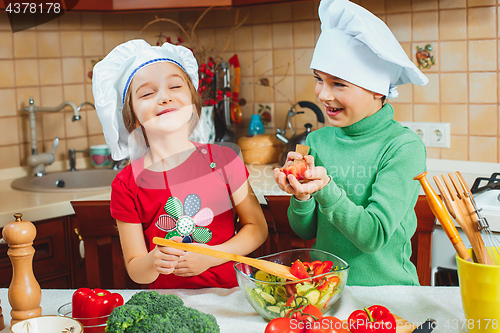 Image of happy family funny kids are preparing the a fresh vegetable salad in the kitchen