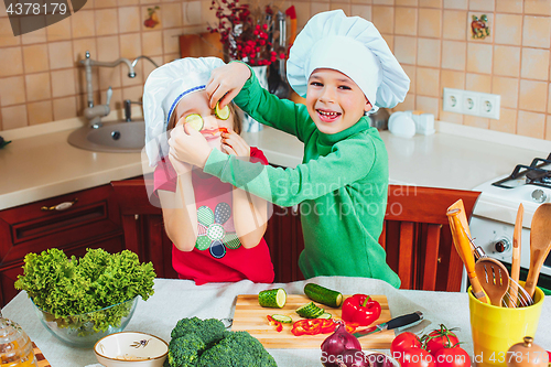 Image of happy family funny kids are preparing the a fresh vegetable salad in the kitchen
