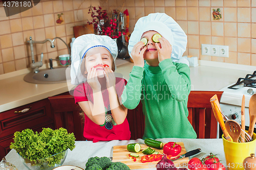 Image of happy family funny kids are preparing the a fresh vegetable salad in the kitchen